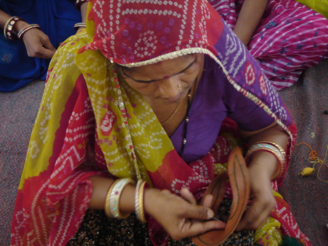 Woman artisan hand stitching leather footwear