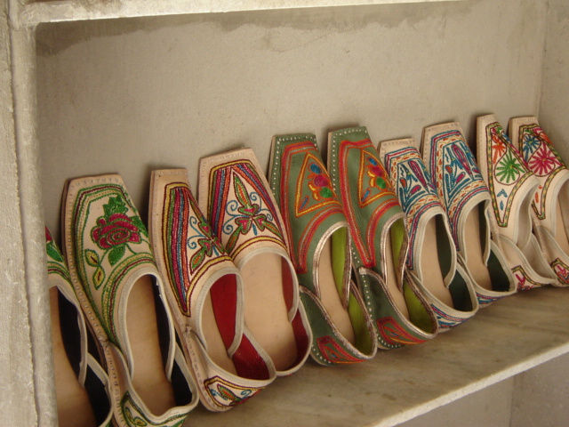 Hand-embroidered leather mojaris arranged on a workshop shelf