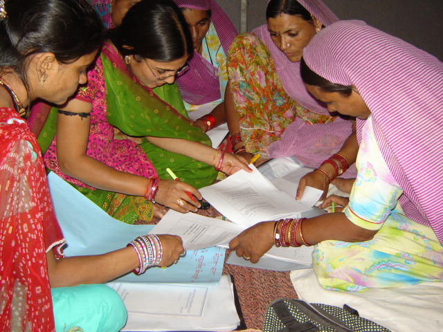 Women gathered around printed records, reading them together